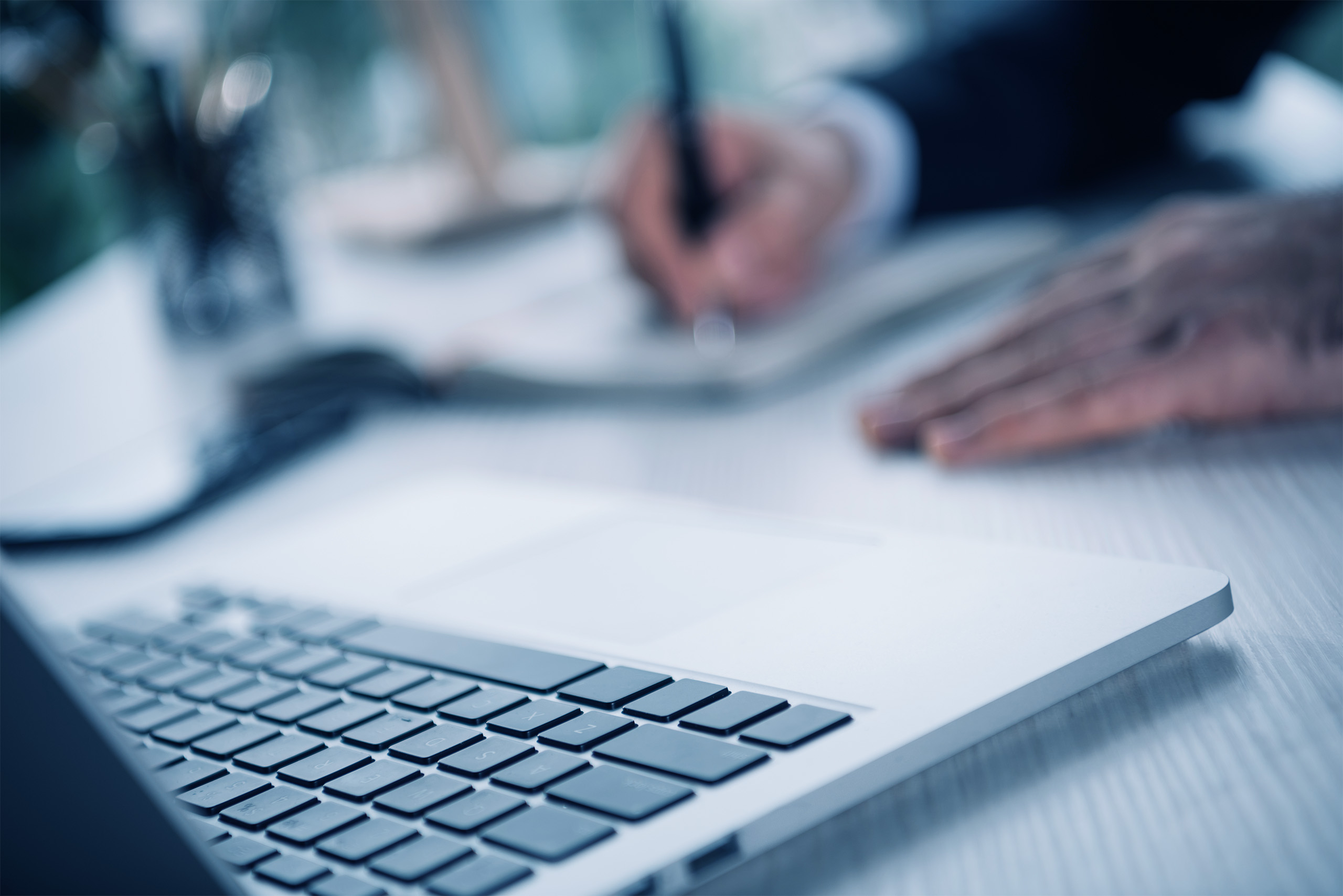 keyboard of laptop with blurred businessman on background